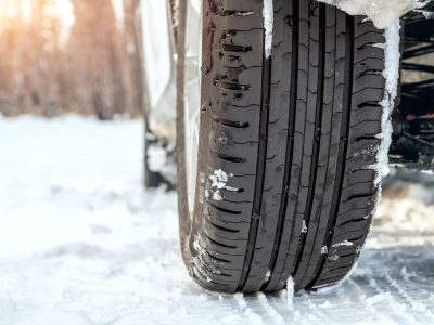 Close-up detail view of car wheel with unsafe summer tread tire during driving through slippery snow Close-up detail view of car wheel with unsafe summer tread tire during driving through slippery snow
